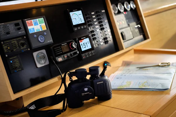 Close up image of binocular and paper map lie on wooden board, view to modern dashboard with navigation system of modern luxury catamaran, no people — Stock Photo, Image
