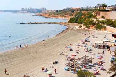 Orihuela, İspanya - 13 Mart 2020: Torrevieja tatil beldesi sahil kentinde bulunan Cabo Roig plajının üzerinde. İnsanlar ılık bahar günlerini Sea, Costa Blanca yakınlarında geçirirler. İspanya