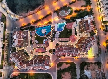 Drone bakış açısı, hava fotoğrafçılığı modern lüks mimari konut kompleksi ve Torrevieja 'nın Punta Prima şehrinde yer alan Akdeniz plaj gece manzaralı yüzme havuzları. İspanya