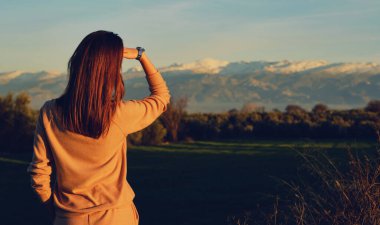 Arkadan bakan zayıf genç kadın Sierra Nevada dağ manzarasının tadını çıkarıyor. Dişi gezgin kış tatili boyunca karla kaplı kayalıkları gözlemliyor. Turizm konsepti. Granada, Endülüs, İspanya