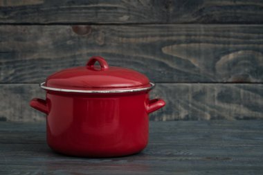 Yeni ve temiz kapalı kırmızı tencere mavi ahşap adam üzerinde