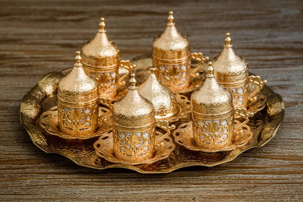 Traditionelle goldene Kaffeetasse in einem Tablett auf Holzgrund — Stockfoto
