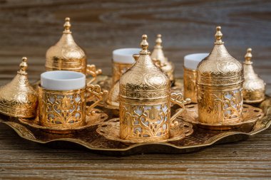 Geleneksel altın kahve fincanı seti içinde bir tepsi ahşap arka plan üzerinde