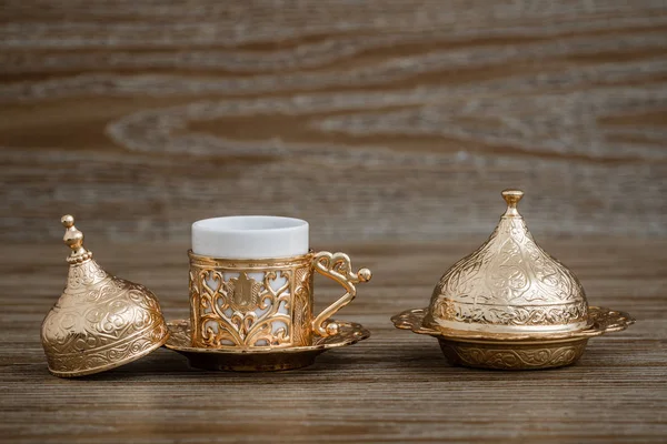 Tradycyjne złote filiżanka kawy zestaw w zasobniku na podłoże drewniane — Zdjęcie stockowe