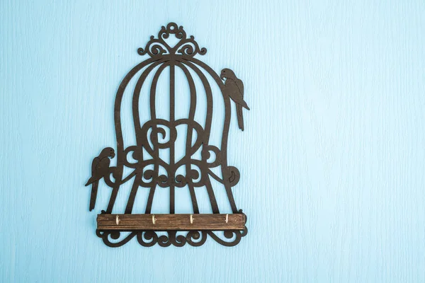 Wooden Key Hangers with Bird Cage Shape on Blue Wooden Backgroun