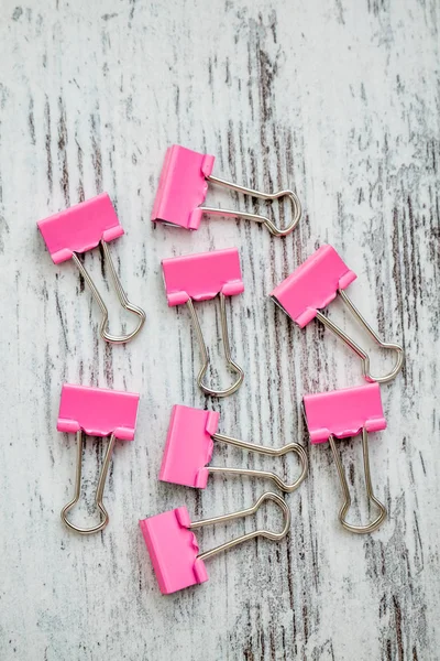 Pinzas de papel aglutinante rosa sobre fondo de madera blanco — Foto de Stock