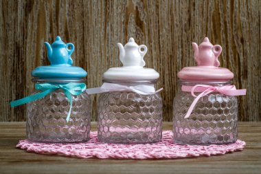 Ahşap masa üzerinde renkli kapakları ile boş cam kavanoz