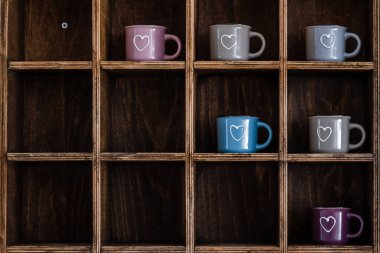 Ceramic coffee mugs on handmade wooden rustic wall shelf clipart