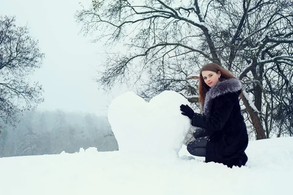 Kvinnan formar ett hjärta av snö — Stockfoto