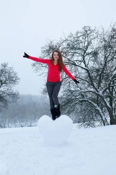 Uma mulher está de pé sobre um coração nevado — Fotografia de Stock