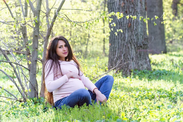 Uma mulher está sentada debaixo de uma árvore de primavera — Fotografia de Stock