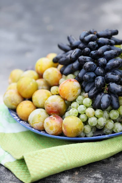 Uvas, ameixas em um prato — Fotografia de Stock