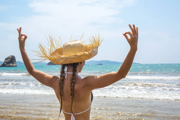 Mujer en un sombrero medita en la orilla del océano —  Fotos de Stock