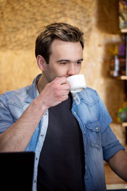 Genç adam kahve içiyor.