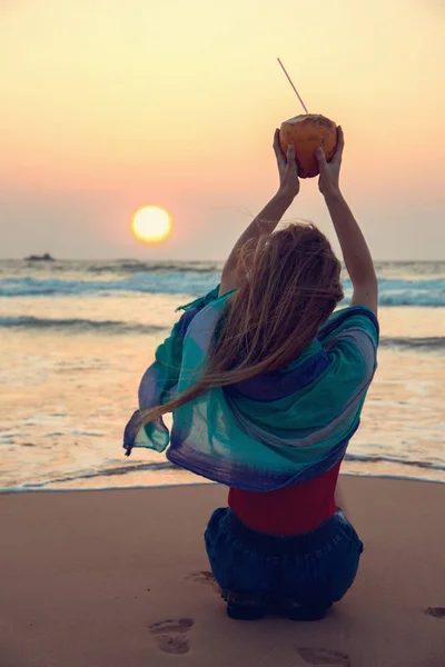 En flicka som håller en kokosnöt ovanför hennes huvud — Stockfoto