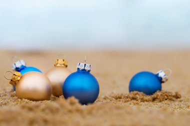 Kumlu sahilde altın ve mavi Noel topları