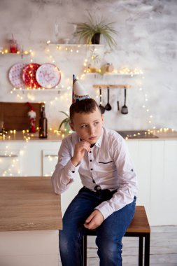 Üzgün çocuk mutfakta oturuyor.