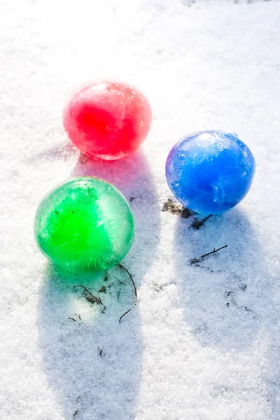 Bolas de hielo multicolores en la nieve en un día soleado, vista superior — Foto de Stock