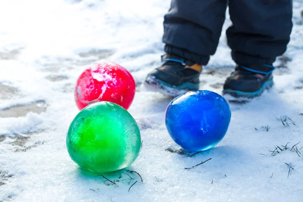 Child plays with frozen balls — Stock Photo, Image