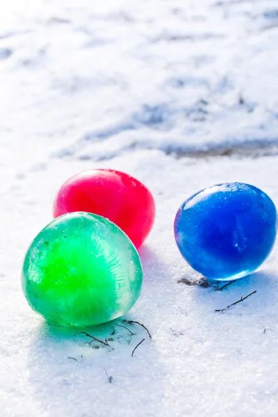 Разноцветные шары со льдом в снегу — стоковое фото
