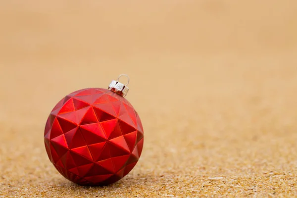 Red Christmas ball on the sandy shore — Stock Photo, Image