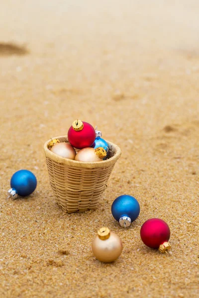 Multi-gekleurde kerstballen in een mand op het zand — Stockfoto