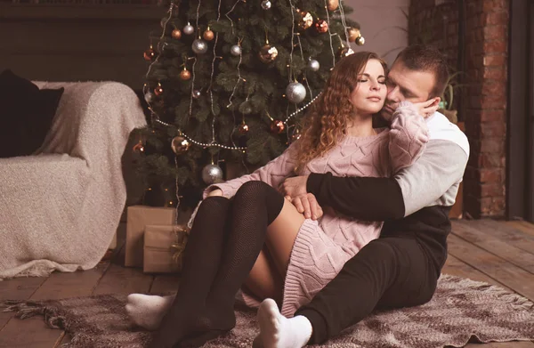 Couple kisses near the Christmas tree on the floor — 图库照片