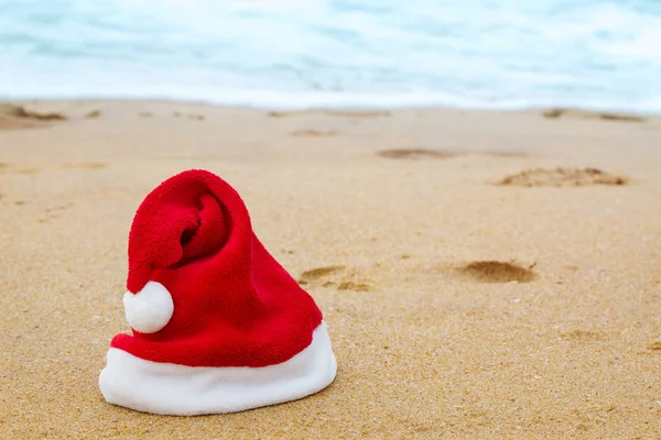 Okyanus kıyısında Noel Baba şapkası — Stok fotoğraf