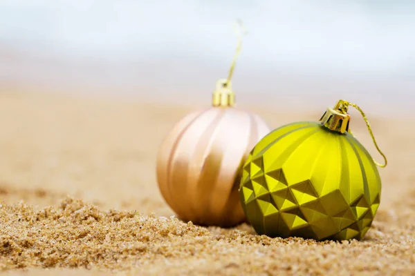 Beige und grüne Weihnachtskugel am Sandstrand — Stockfoto