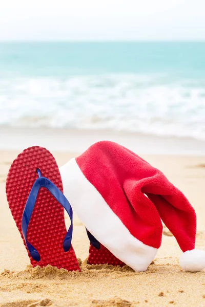 Turkuaz okyanusun yanında Noel Baba şapkası ve ayakkabılar. — Stok fotoğraf