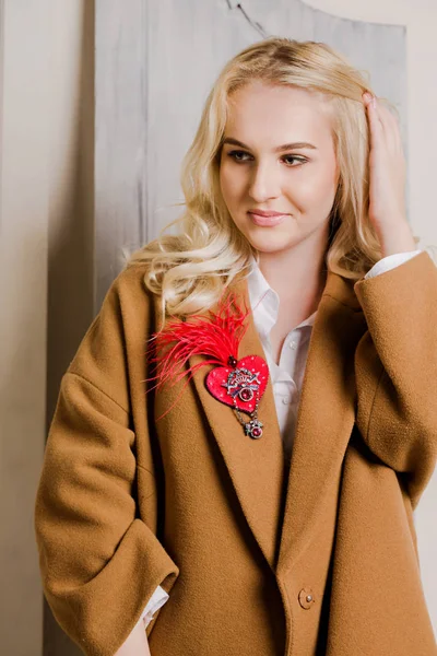 Portrait of a young woman with a red heart-shaped brooch — Stock Photo, Image