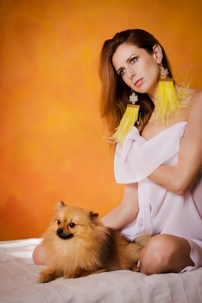 Красивая женщина, завернутая в простыню на кровати с собакой — стоковое фото