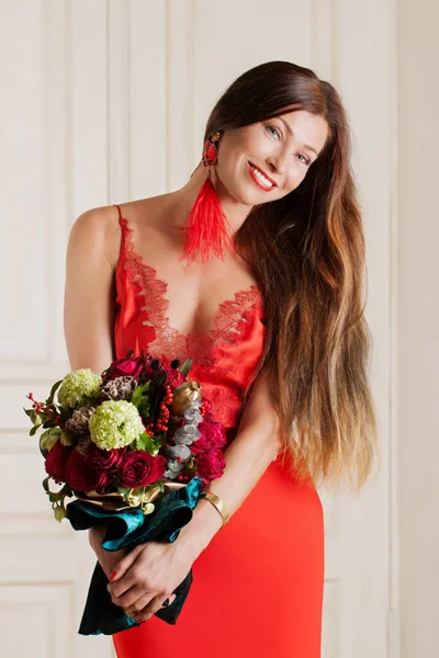 Belle femme en vêtements rouges avec un bouquet de fleurs — Photo