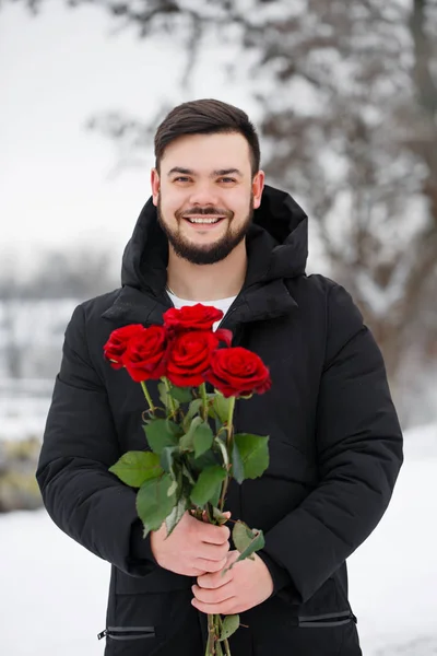 Beau jeune homme aux roses rouges, en plein air — Photo