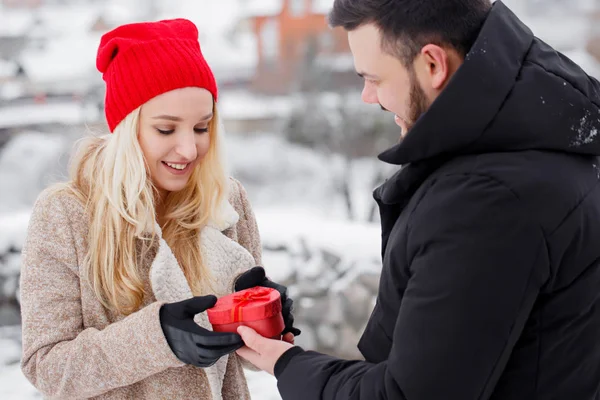 A guy gives his girlfriend a heart-shaped box — Stock Photo, Image