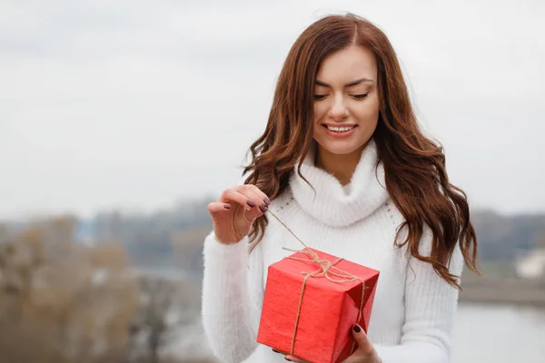 Το όμορφο κορίτσι κρατάει ένα κουτί με ένα δώρο στα χέρια της. — Φωτογραφία Αρχείου