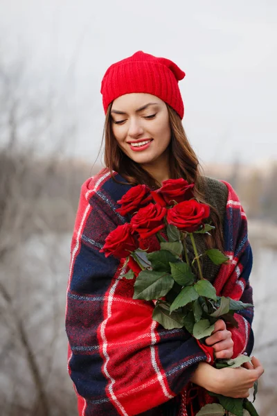 Krásná brunetka s kyticí rudých růží v rukou — Stock fotografie