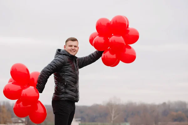 Lustiger Mann mit roten Luftballons — Stockfoto