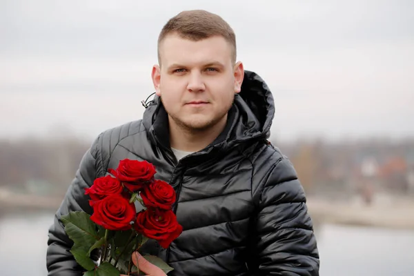 Handsome young man with roses, outdoors
