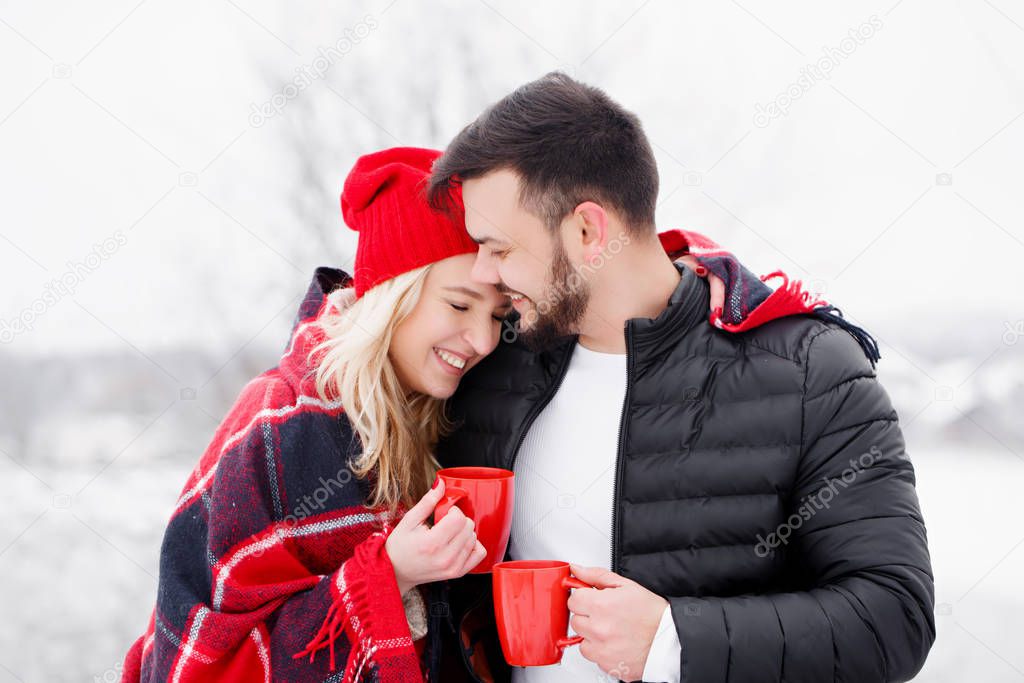 Happy couple at a picnic in winter they drink coffee