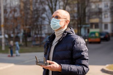 Koruyucu maskeli bir arazi mühendisi bir kuadrokopteri kontrol ediyor. Coronavirus Koruma Konsepti