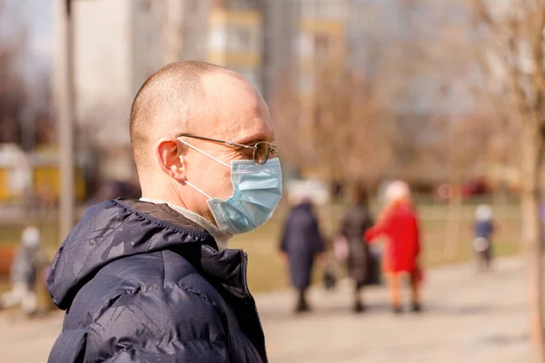 A man in a protective mask walks down the street. Coronavirus Protection Concept