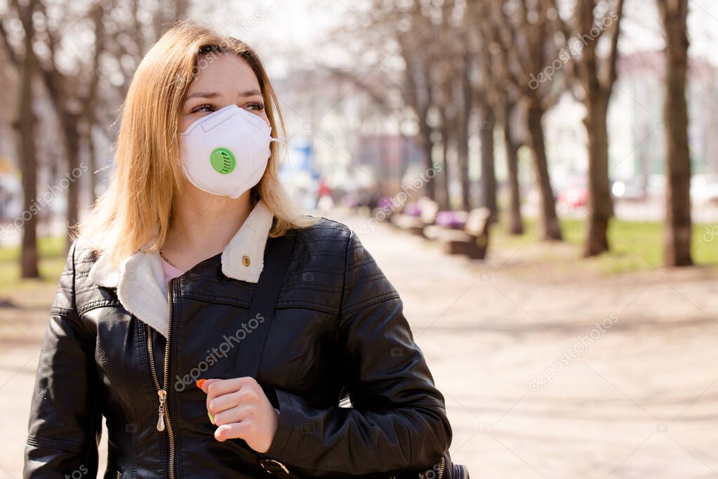 Young beautiful woman in a protective mask walks outdoors. Coronavirus Protection Concept