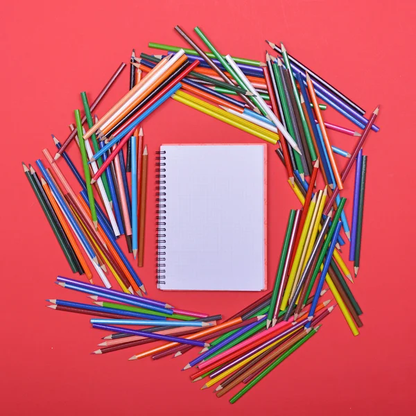 Montón de lápices de madera de colores alrededor del libro de notas en blanco - Flat l — Foto de Stock