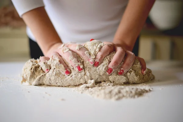 Les mains de la femme pétrissent la pâte sur une table — Photo
