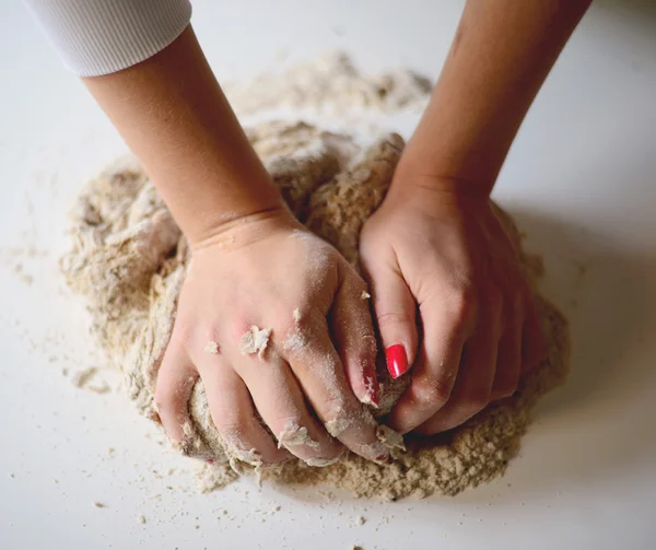 Les mains de la femme pétrissent la pâte sur une table — Photo