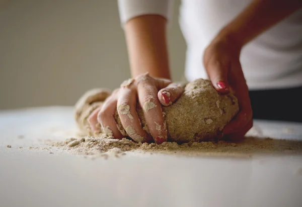 Las manos de la mujer amasan la masa sobre la mesa — Foto de Stock