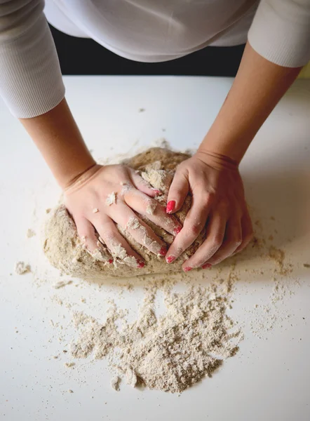 Les mains de la femme pétrissent la pâte sur une table — Photo