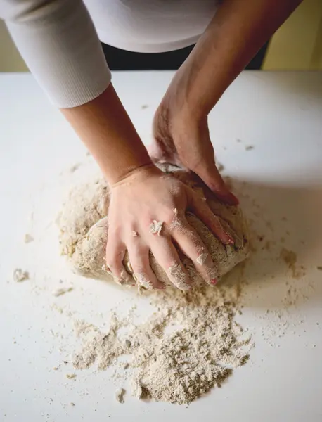 Les mains de la femme pétrissent la pâte sur une table — Photo