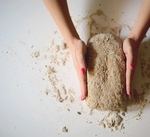 As mãos de mulher amassam a massa de farinha em uma mesa — Fotografia de Stock